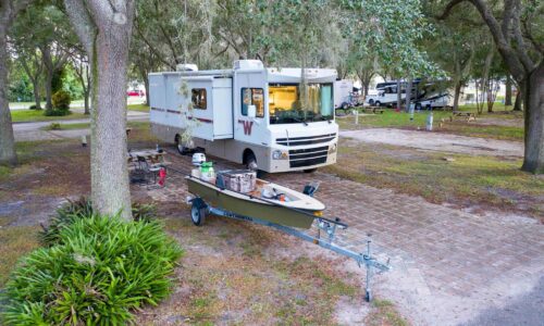 Motorhome and boat under an oak tree at Camp Mack, a Guy Harvey Resort, RV campsite near Lake Wales, FL