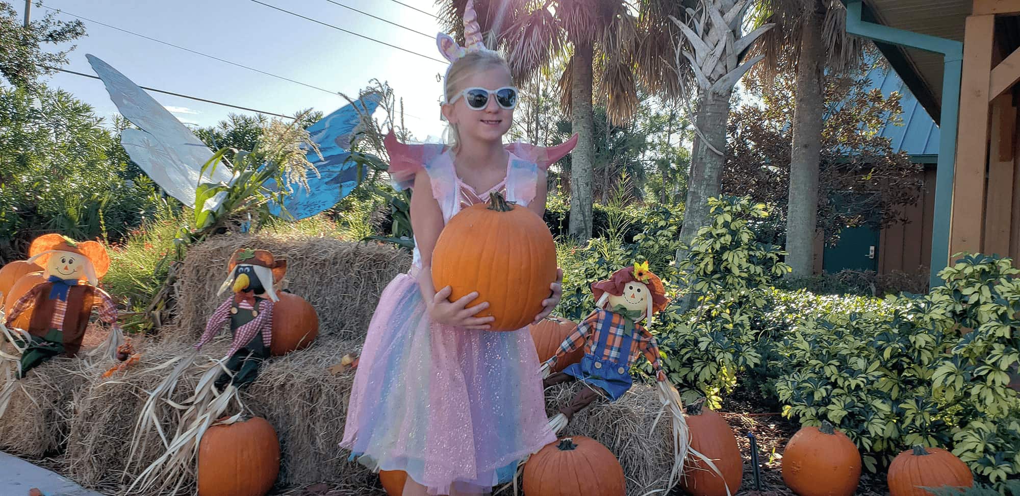 child holding pumpkin outside of Central Florida Visitor Information Center during Ghosts, Goblins, & Goodies