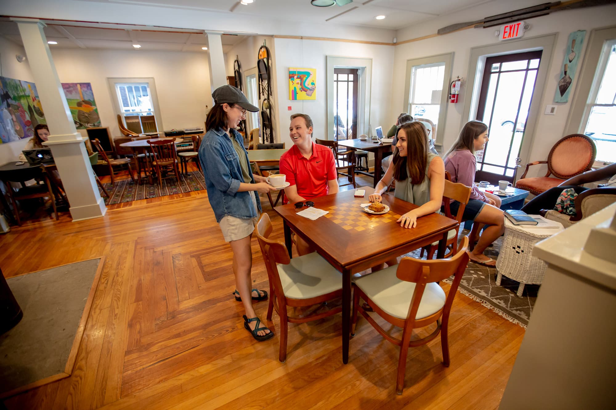 Staff bringing coffee to customers sitting at table inside Hillcrest Coffee in Lakeland, FL