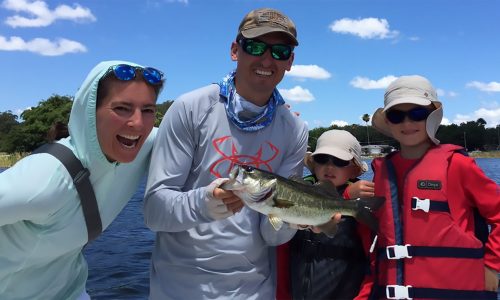 parents and 2 sons with lake in background. dad holding fish. TMC Guide Service